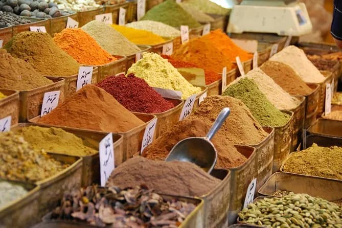 Spices heaped in tins at a market stall with a metal scoop