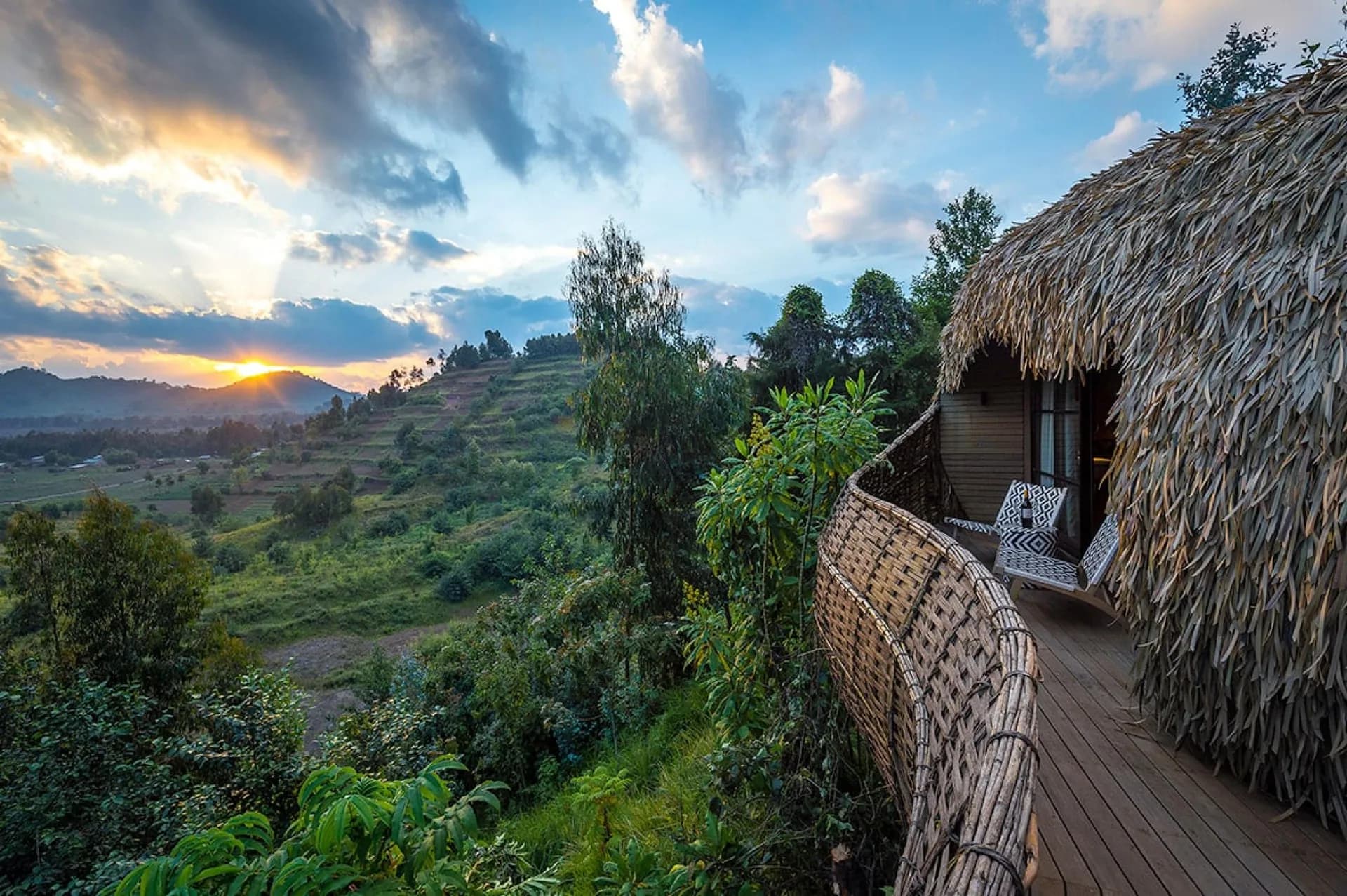 Lodge buildings on a terraced Rwandan hillside under cloud
